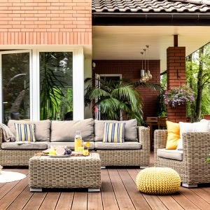 deck design ideas Yellow pouf, rattan armchairs and flowers on wooden patio